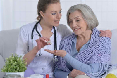 nurse giving medication to senior woman